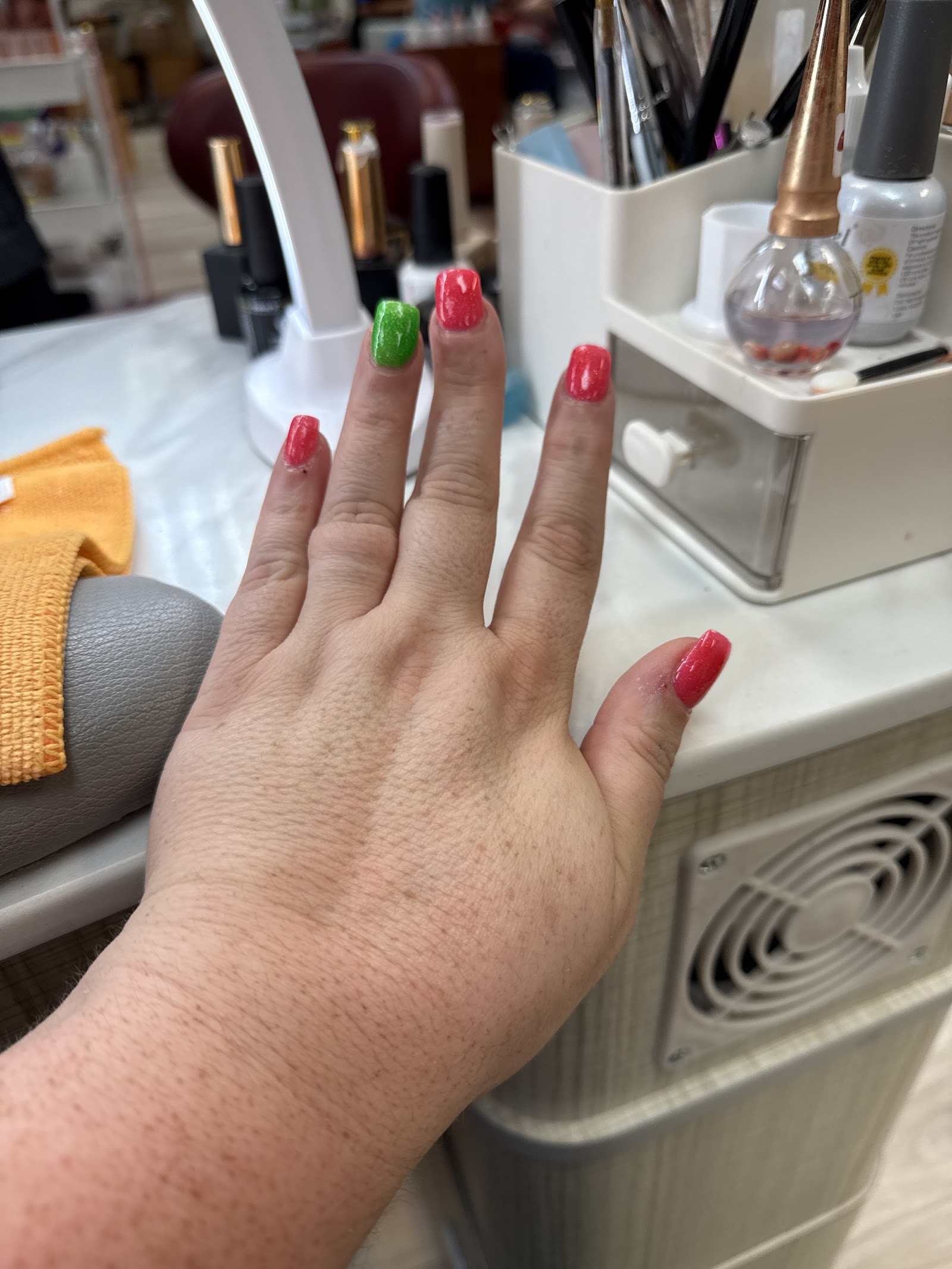 Coral nails with a single lime-green accent nail