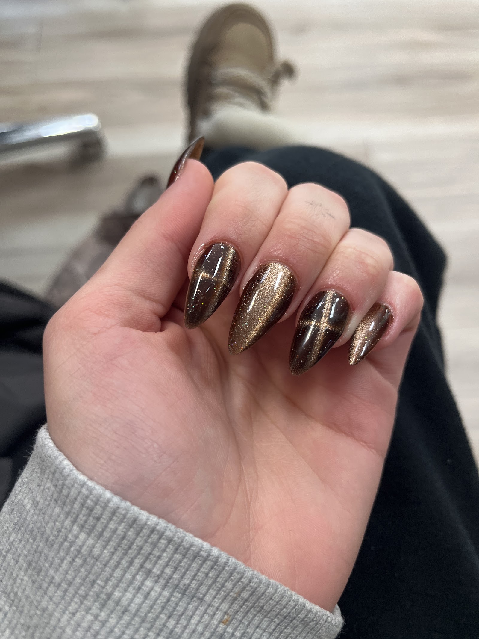 Stiletto nails in brown and gold cat-eye with fine cross detailing