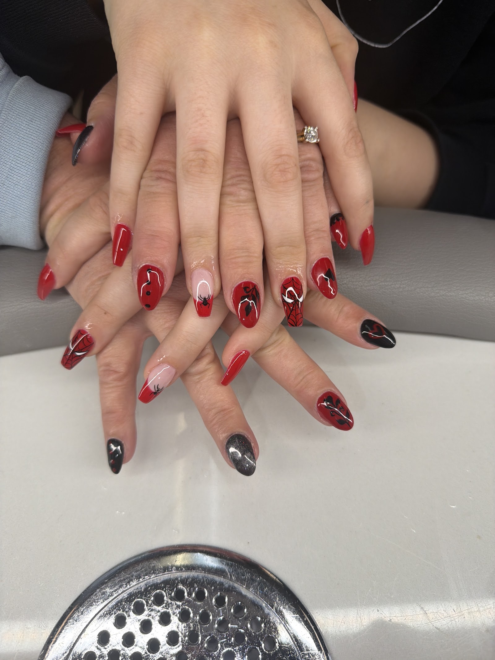 Long red and black nails with marble and drip artwork across two hands
